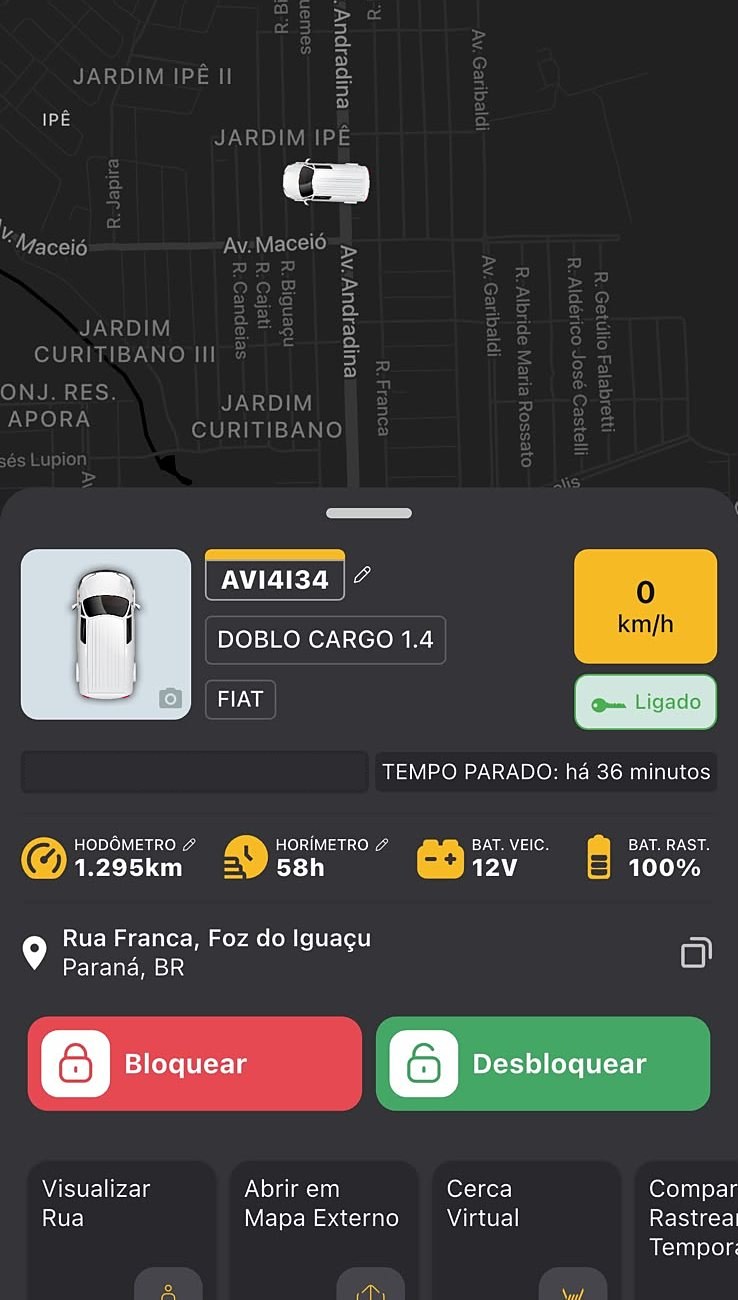 Tela do CarreGo Auto: veículo no mapa, ignição ligada, 0 km/h, tempo parado há 36 minutos, hodômetro, horímetro, bateria do veículo 12V, bateria do rastreador 100%, endereço e botões de bloquear e desbloquear